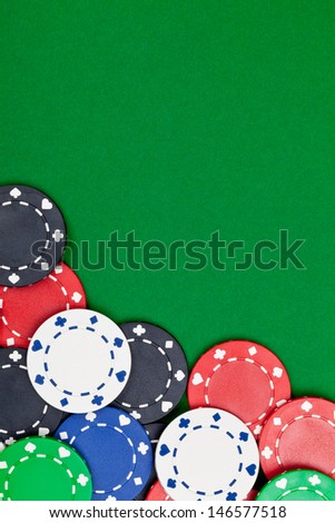 Different casino chips on green table background with copyspace