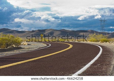 Curved road in the desert with dramatic sky
