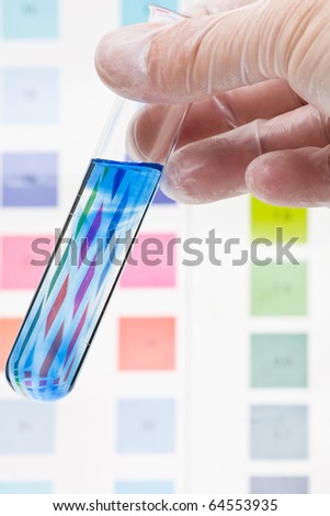 Hand holding test tube with pH indicator comparing color to scale