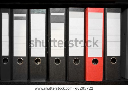 Row of black archive folders with one red folder