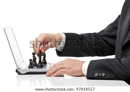 Businessman with chess figures on laptop keyboard - strategy or management concept