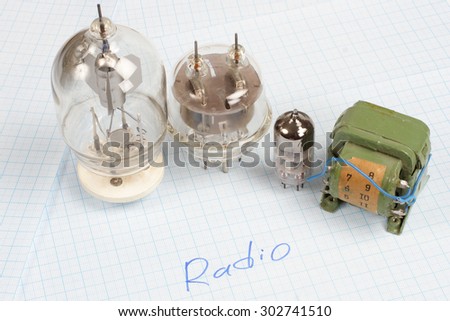 old vacuum tube (electron tube) and transformer on graph paper background