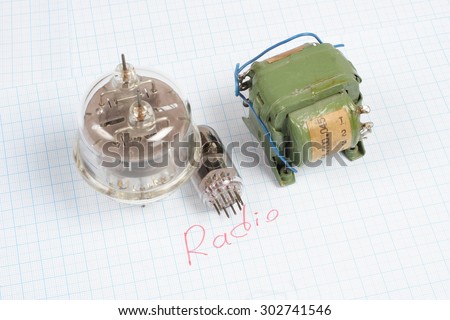 old vacuum tube (electron tube) and transformer on graph paper background