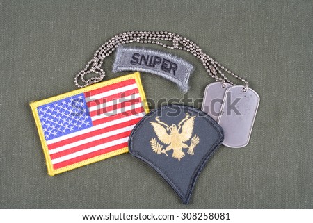 KIEV, UKRAINE - August 21, 2015.  US ARMY Specialist rank patch, sniper tab, flag patch and dog tag on olive green uniform