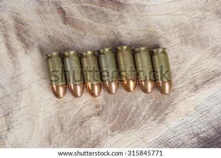 The .45 caliber cartridge on wooden background