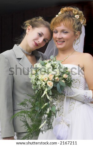 young beauty bride with girl friend and bouquet of cream roses