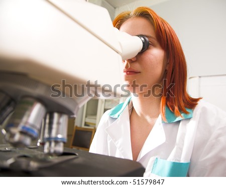 young woman with microscope in research center