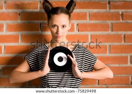 woman with vinyl plate on brick wall background