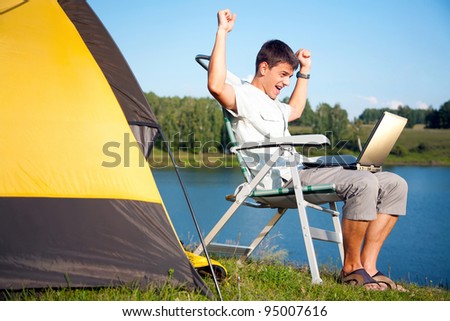 young man with laptop near the tent