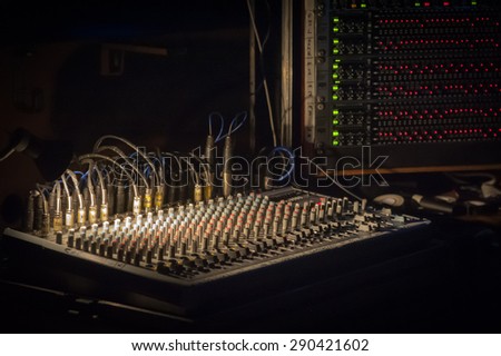 spotlight illuminating a soundboard mixer at a live music event