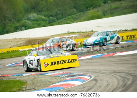 THRUXTON, UNITED KINGDOM - MAY 1: Steve Parish gets a large sponsorship banner stuck to the front of his car during a Porsche Carrera Cup race on May 1, 2011 in Thruxton, UK.
