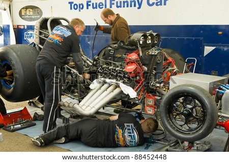 NORTHAMPTONSHIRE, UK - OCT 29: Mechanics working on a top fuel funny car at the Flame and Thunder drag-racing event on Oct 29, 2011 at Santa Pod Raceway in Northamptonshire, UK