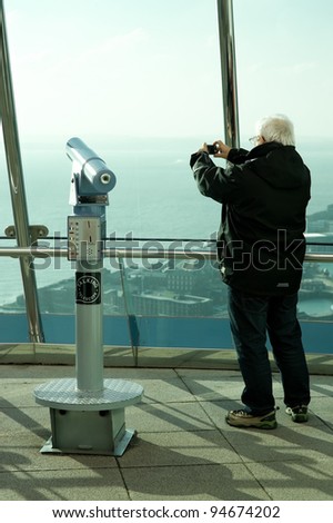 PORTSMOUTH, UK - FEBRUARY 1: Man photographing the view from the 560ft (170m) Spinnaker Tower, Britains highest public observation platform in Portsmouth, UK - February 1, 2012