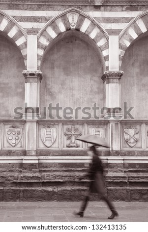 Exterior Facade of Santa Maria Novella Church; Florence; Italy with Woman Walking with Umbrella in Black and White Sepia Tone