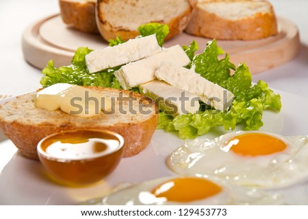 Sunny side eggs, honey and cheese breakfast (focus on cheese)