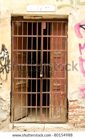 Old door with metal grill locked with a chain