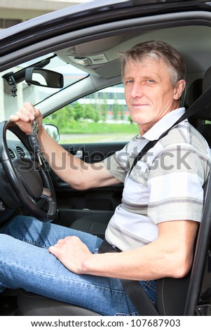 Happy mature driver with car key sitting in own land vehicle