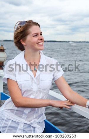 Attractive smiling woman with sunglasses in white shirt standing on ship deck