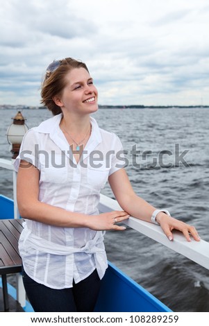 Attractive Caucasian woman with sunglasses in white shirt standing on ship deck