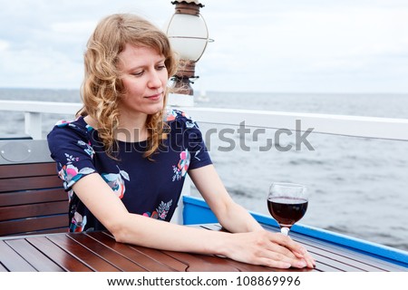 Pensive woman in dress with wine glass sitting at the table