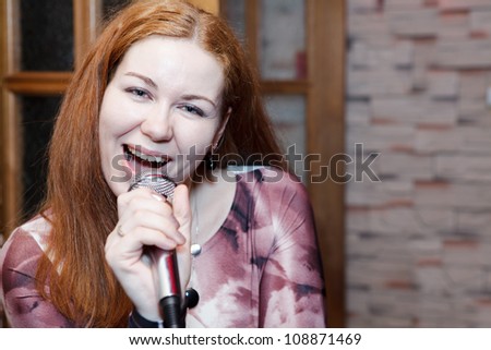 Young woman a singer sings a song with microphone. Copyspace