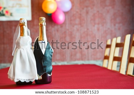 Two bottles of champagne wearing like a bride and groom on table. Copy space