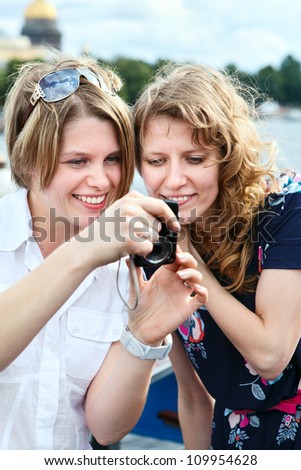 Two beauty women looking at screen of simple hand-held camera