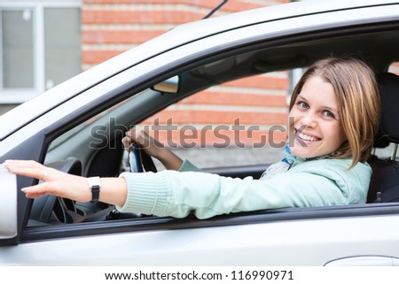 Young driver a blond woman holding back car mirror