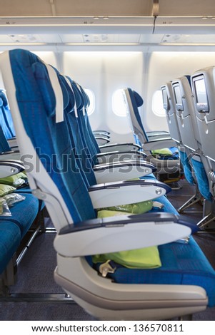 Comfortable seats in aircraft cabin with screens in chairs back