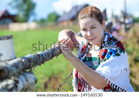Attractive village woman with headscarf posing near fence
