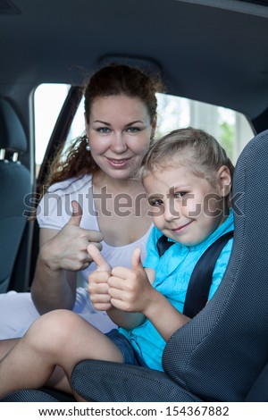 Mother and child with thumb up gesture in car safety seat