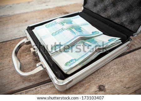 Russian money in order inside of steel suitcase, on wooden floor