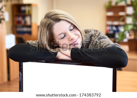 Young woman sleeping over blank screen of monitor in office