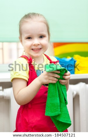 Little girl with smile on face in red sundress with green towel in hands