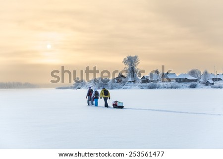 People traveling over frozen lake at beauty sunset, cold weather