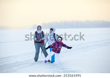 Three women different ages standing on ice of frozen lake at strong cold weather