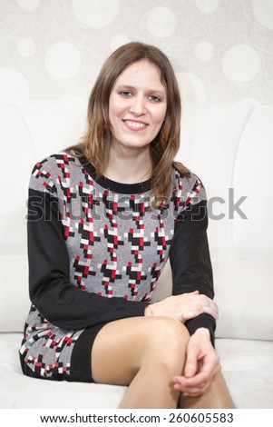 Young beautiful woman sitting alone on white leather couch