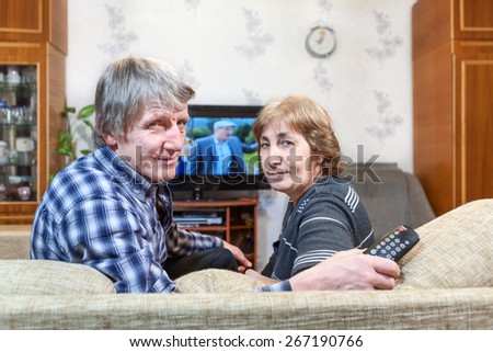 Senior Caucasian couple sitting in front of TV and turning back on couch