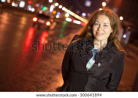 Joyful woman at night city street wearing in black coat, copyspace portrait