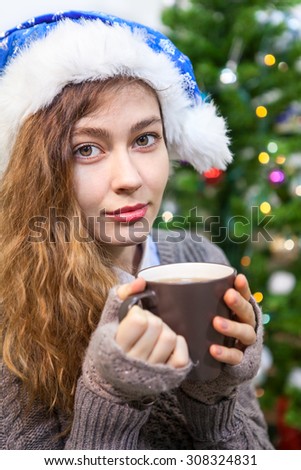 Pretty woman portrait, holding tea mug in hands and looking at camera