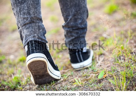 Unrecognizable man in rubber shoes stepping on footpath, rear view, close-up