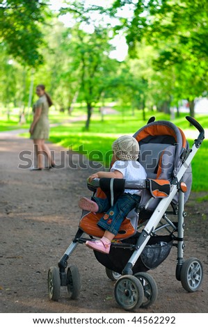Mother leaves own child in perambulator. Park, outdoor.