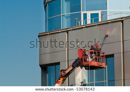 Window washing on high-rise office building in crane beam