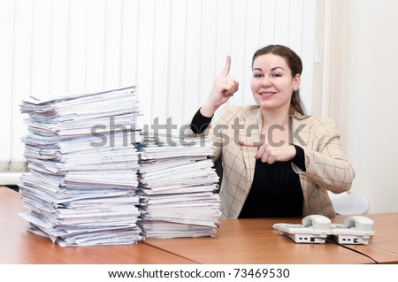 Young caucasian woman near pile from project drawings blueprints showing on it