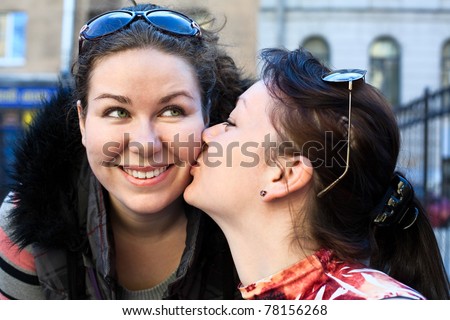 Young beautiful woman kissing a girlfriend in cheek