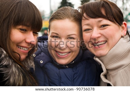 Smiling three women in winter clothes standing together