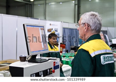 MOSCOW-MAY 18: Man operates woodworking machine with CNC at the international exhibition of professional furniture EEM Euroexpofurniture on May 18, 2011 in Moscow