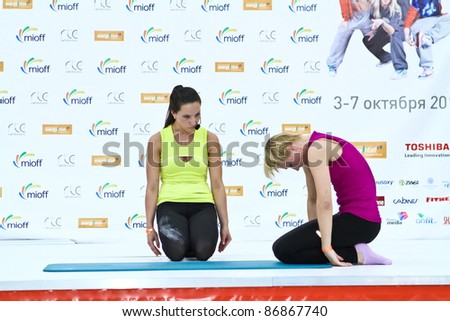 MOSCOW - OCTOBER 5: Woman doing stretching by leadership of coach at the international exhibition of the fitness and wellness industry, MIOFF on October 5, 2011 in Moscow