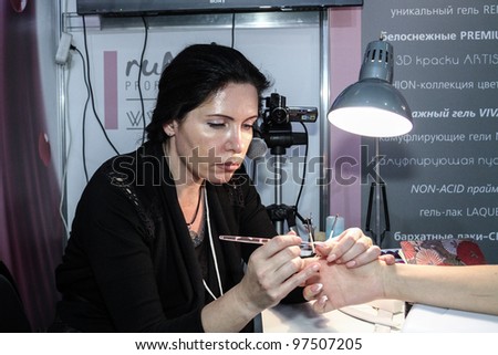 MOSCOW - OCTOBER 26: Master make nail extension at the international exhibition of professional cosmetics and beauty salon equipment INTERCHARM on October 26, 2011 in Moscow