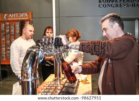 MOSCOW-APRIL 27: Man pouring beer to glass from beer tap at the international exhibition of market production beer, and low alcohol drinks Brewer on April 27, 2011 in Moscow